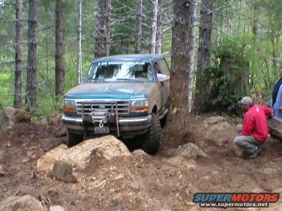 1995 Ford Bronco navigating a rocky, wooded trail. Winch is mounted on the front bumper