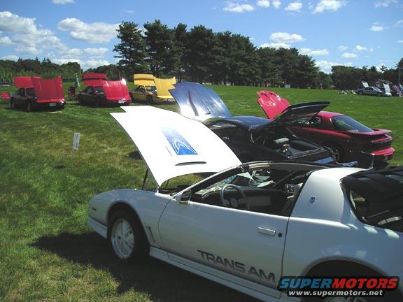 White Pontiac Trans Am with hood up, other cars in background