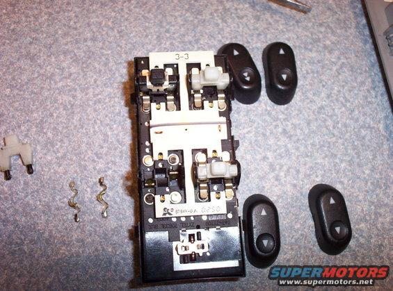 Disassembled car door window switch assembly with separate buttons and springs