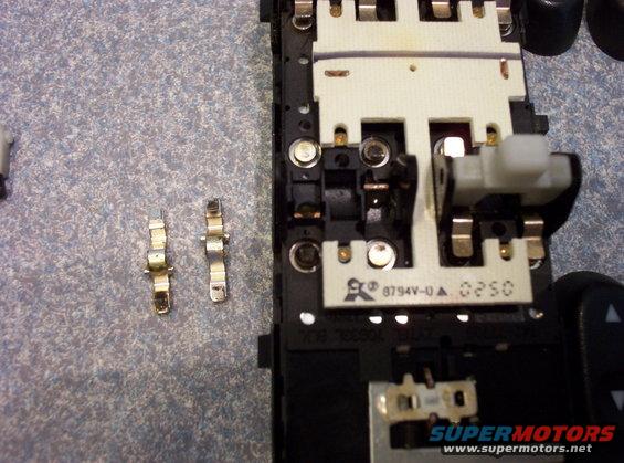 Close-up of car interior electronic switch assembly with two detached metal connectors