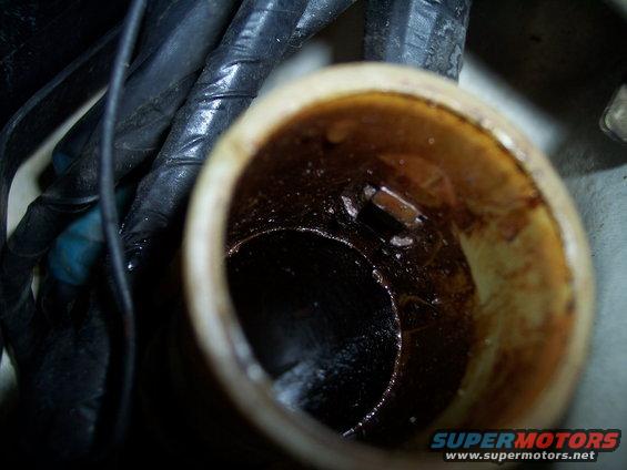 Close-up of a dirty engine oil filler cap opening with visible grime and some wiring