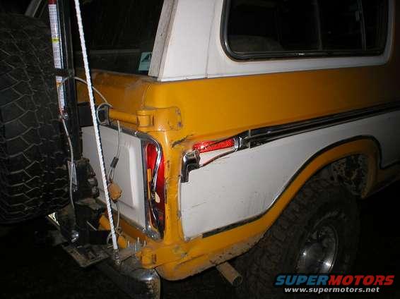 Yellow and white 1978 Ford Bronco rear quarter panel with spare tire mounted on the left