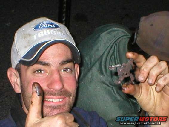 Man wearing a Ford Trucks hat gives a thumbs up while holding a small, dark metal object