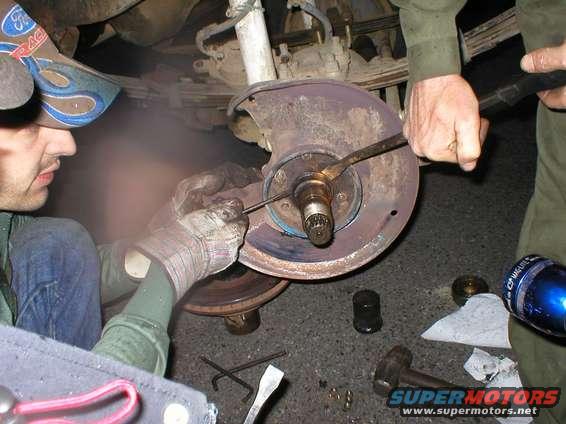 Mechanic working on brake rotor and hub assembly, possibly a 1978 Ford Bronco
