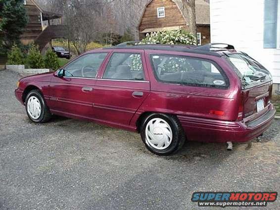 Maroon station wagon parked on gravel, seen from the rear quarter