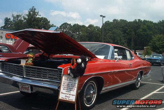 Red 1968 Ford XL coupe with hood open, parked at an outdoor event