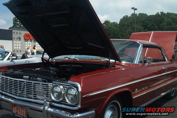 Red 1964 Chevrolet coupe, front view, hood open, showing engine