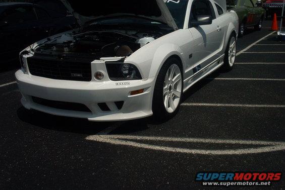 White Ford Mustang with hood open, showing engine. Visible text '302'