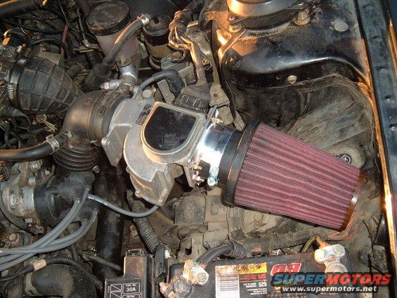 Engine bay with a red cone air filter attached to the throttle body