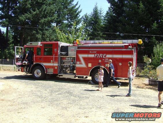 Red fire truck with "MILANE FIRE" text on the side, parked outdoors with people nearby