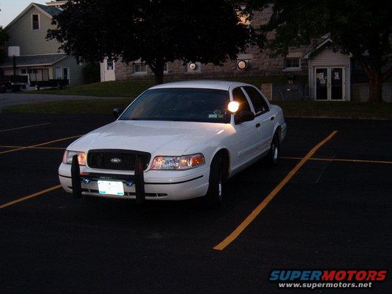 White 1999 Ford Crown Victoria police car with push bumper parked in a lot