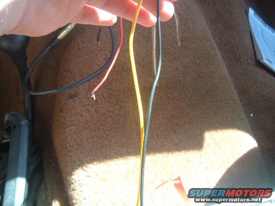Hand holding wires over brown carpet inside a vehicle