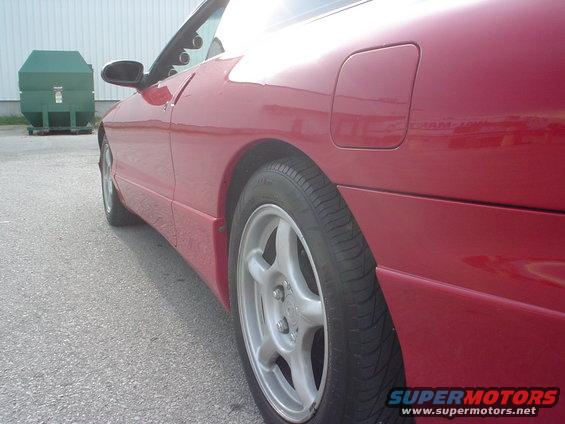 Side view of a red 1996 Ford Probe parked next to a green dumpster
