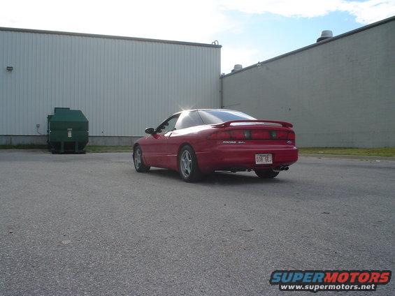 Red 1996 Ford Probe parked near a dumpster and industrial buildings