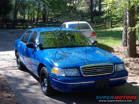 Blue sedan with black wheels and chrome grille, parked on a driveway
