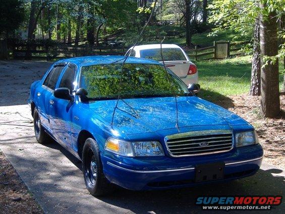 Blue sedan with black wheels and antennas parked on a driveway