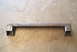 1983 Ford Bronco - This is a metal crossmember part, likely for a vehicle, shown on a concrete surface.