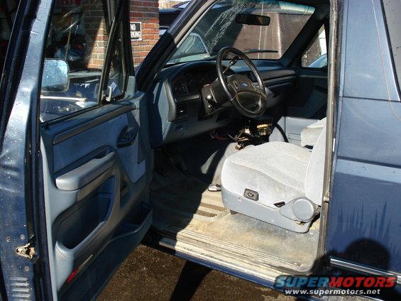 Driver's side interior of a blue SUV, showing the dashboard, steering wheel, and front seat