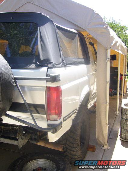 Rear view of a white 1992 Ford Bronco with a soft top, parked under a canopy