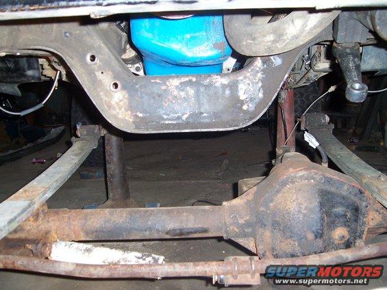 Undercarriage of a vehicle with a blue oil pan and rusty differential