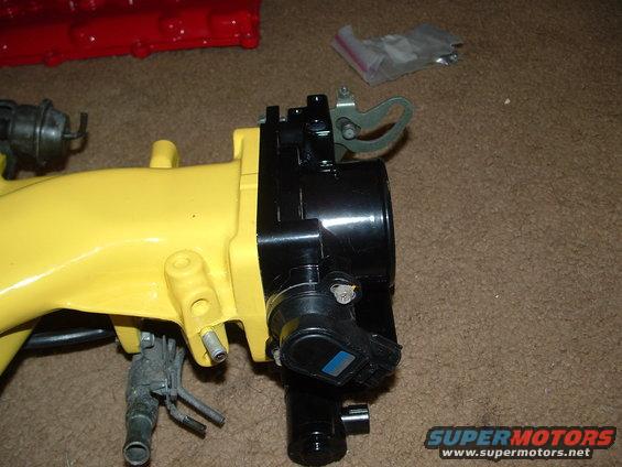 Yellow intake manifold with black throttle body and blue sensor