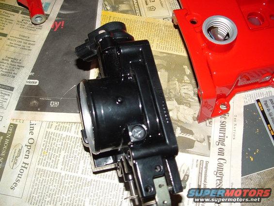 Black throttle body and red valve cover on newspaper