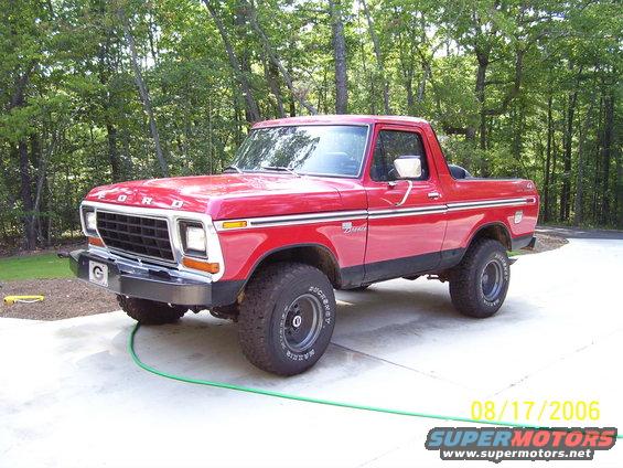 Red 1978 Ford Bronco with chrome grille and side trim, parked on concrete