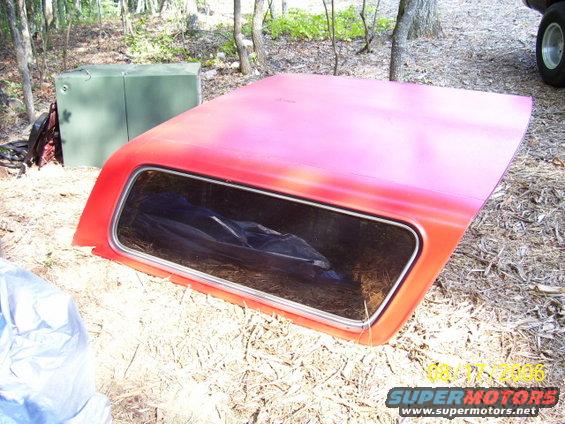 red truck cap with a window, lying on the ground outdoors