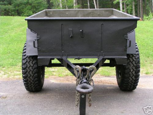 Rear view of a black military-style trailer with large off-road tires
