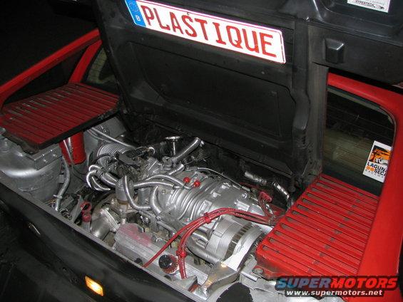 Car's engine bay with a license plate that says 'PLASTIQUE' on the hood