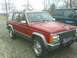 1992 Jeep Cherokee - Red 1992 Jeep Cherokee with roof rack parked outdoors next to a dark green truck.
