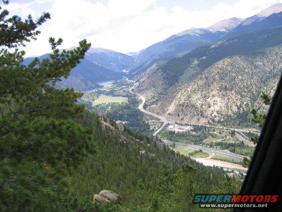 View from a car window looking down on a valley with a highway and a lake