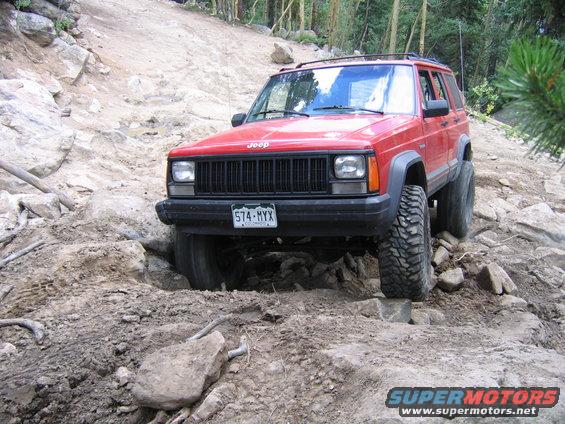 Red 1996 Jeep Cherokee navigating rocky terrain