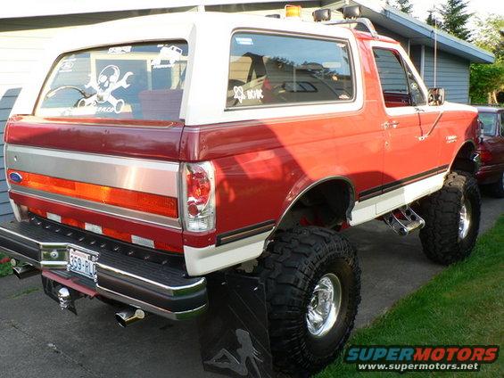 1989 Ford Bronco, rear view, red and white with large tires and custom decals