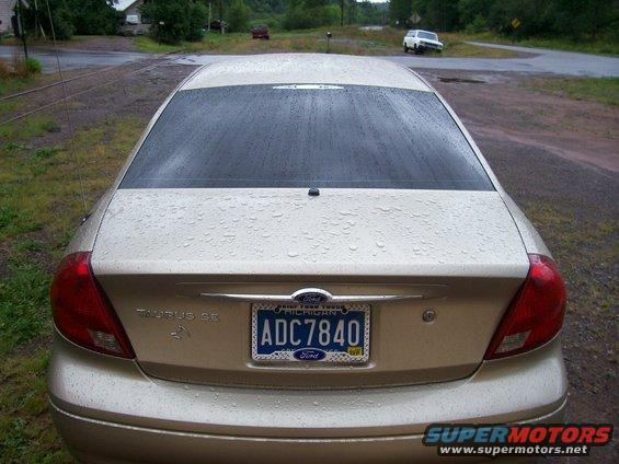 Rear view of a gold 2000 Ford Taurus SE with a Michigan license plate. It's raining