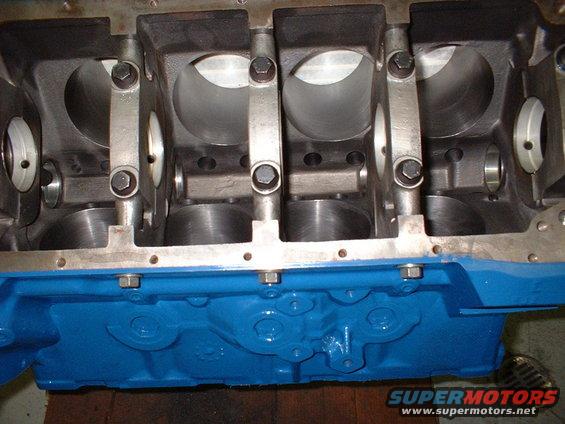 Engine block with connecting rods visible inside cylinders