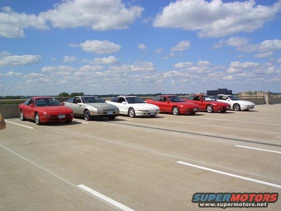 Several 1993 Ford Probes parked in a line on a rooftop parking lot