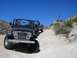 1979 Chevrolet C/K Pickup - A black Jeep Wrangler leads a pickup truck on a dusty off-road trail under a clear blue sky.