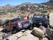 1979 Chevrolet C/K Pickup - A blue 1979 Chevrolet C/K Pickup navigates rocky terrain alongside a red Jeep Cherokee.