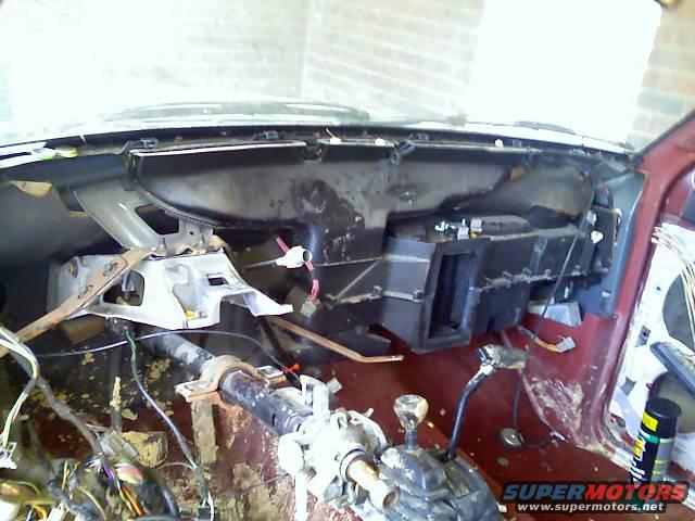 Vehicle interior with dashboard removed, showing exposed wiring and HVAC components