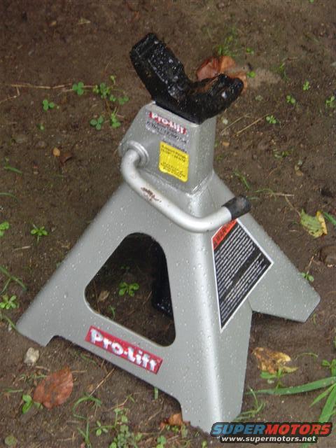 Silver Pro-Lift jack stand with black rubber saddle, on wet ground
