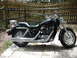 2004 Honda Shadow Sabre VT 1100 - A black motorcycle is parked outdoors on a paved patio area, with a wooden fence behind it.