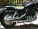2004 Honda Shadow Sabre VT 1100 - A black motorcycle with chrome exhaust pipes and engine details is parked on a paved surface.