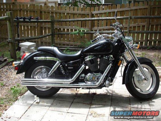 2004 Honda Shadow Sabre VT 1100 motorcycle, side view, parked on patio with wooden fence behind