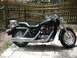 2004 Honda Shadow Sabre VT 1100 - Side view of a black 2004 Honda Shadow Sabre VT 1100 motorcycle parked outdoors on a paved surface.