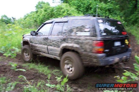 Mud-covered black Jeep Grand Cherokee driving off-road