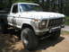 1990 Ford Bronco - This white 1979 Ford F-Series pickup truck is shown from the front quarter angle, lifted with large off-road tires.