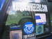 1990 Ford Bronco - A collection of stickers adorns the window of a blue vehicle, obscuring the interior and the view outside.