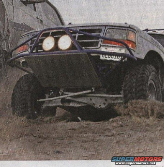 Front view of a modified 1992 Ford Bronco with a custom bumper and off-road lights, driving on dirt