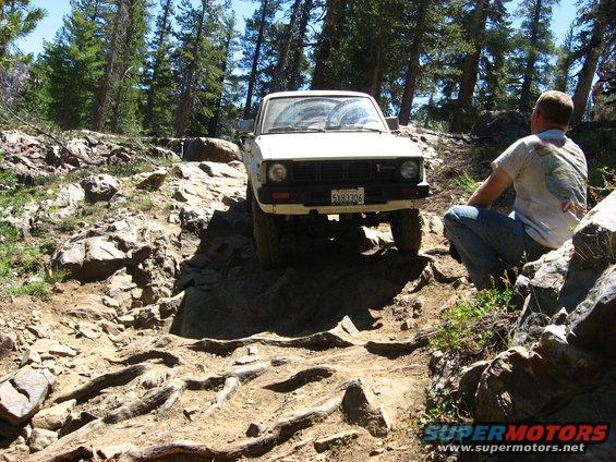 White pickup truck navigating a difficult rocky trail. License plate reads 5X93306
